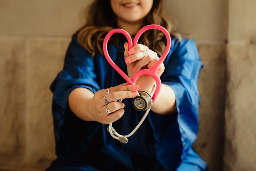 A woman holds up a red stethoscope in the shape of a heart.