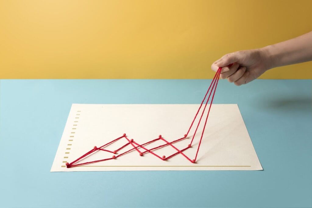 A photo of a hand pulling the end of a red string growth chart from a piece of white paper.