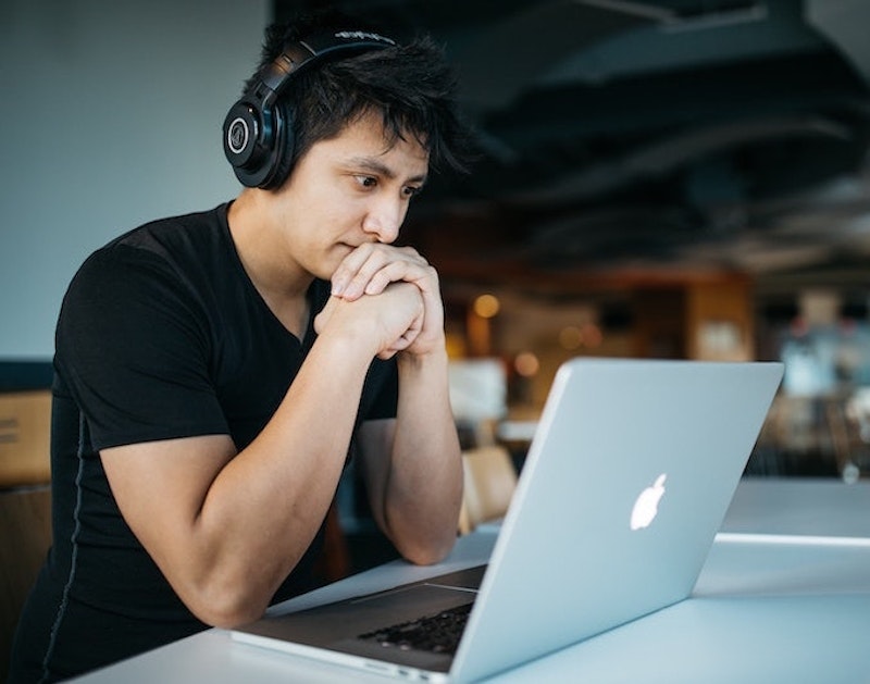 Online MBA student with headphones seated in front of laptop computer and taking an online course from the Weatherhead School of Management 