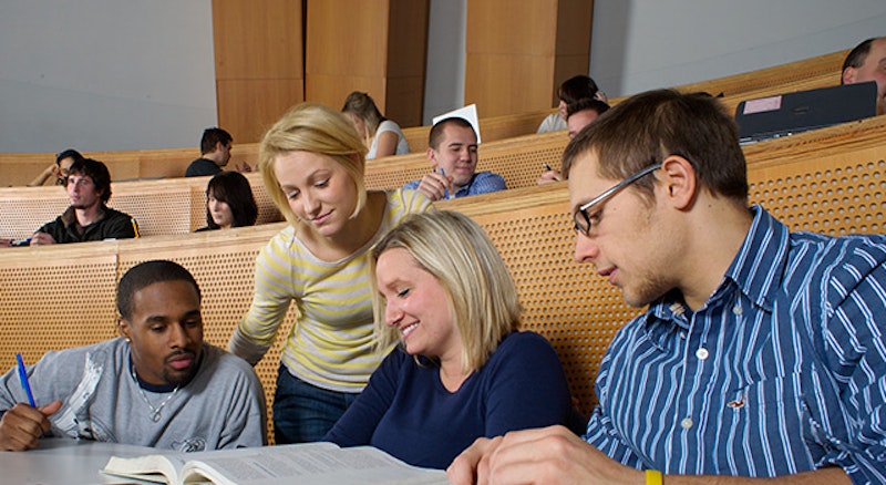 MBA students working together over an MBA project in a lecture hall