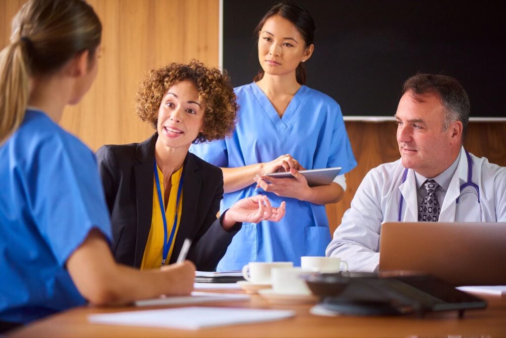 In a conference room, a healthcare manager discusses policy with several medical practitioners.