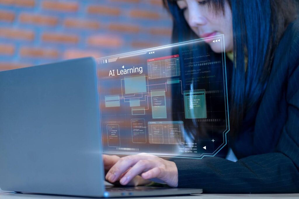 A computer science student works at a laptop computer whose screen image overlays the photograph; the screen features the text "AI Learning"