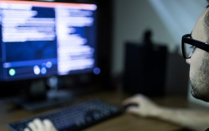 A student studies code on a computer screen.